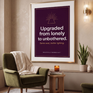 Digital print with a dark purple background and a gold border. At the top is a simple line art illustration of a pyramid with light rays shining from the flat peak. Bold white text reads "Upgraded from lonely to unbothered." Below it, gold cursive text reads "Same seat, better lighting." The text "BEAUTIFULLY BURNED OUT™" is centered at the bottom in small capital letters.